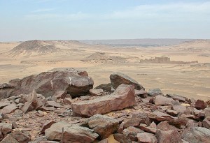 A stone workshop with an unfinished statue and St. Simeon's monastery in the background
