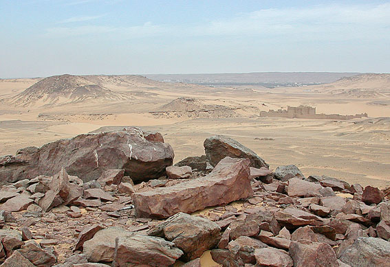 A stone workshop with an unfinished statue and St. Simeon's monastery in the background