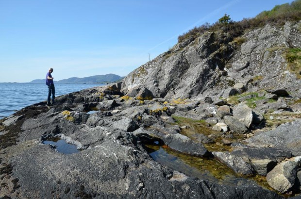 Torbjørn Løland showing one of the  millstone quarries in Hyllestad, at Otringsneset just by the fjord. Photo by Per  Storemyr