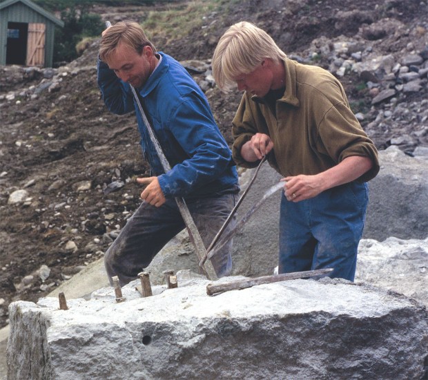 SPLITTING: Steinhoggerne Atle Elverum og Henning Grøtt deler opp blokk ved hjelp av kiler med blekker i kleberbruddet på Bubakk ved Kvikne i 1995. Dette var et av de aller siste steinuttakene i bruddet. Foto: Per Storemyr