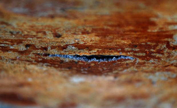 Frost heaving in masonry I: Ice crystals growing between hard stone (gneiss) and a layer of lime wash, lifting the wash, creating a crack and eventually destroying the lime wash. Masonry of limekiln in Hyllestad, Western Norway. Width of image c. 3 cm. Brown colour is due to rust formation from oxidising iron sulphides in a stone above and does not influence frost weathering. Photo by Per Storemyr