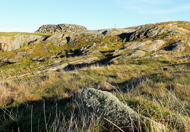 Stumpen av Sonkakrossen. En lavbevokst stein i fremkant, ikke langt fra ei svær gravrøys fra bronsealderen. Foto: Per Storemyr
