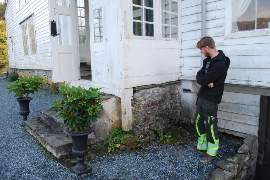 Alexander sjekker grunnmurene. Det er helt klart at de er veldig slitne og at noe må gjøres. Svaret er kalk! Foto: Per Storemyr