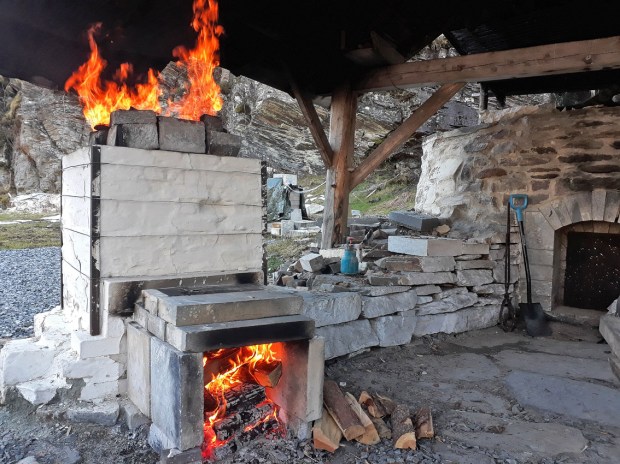 Ovnen er fyrt opp og etter noen timer er toppen dekket delvis til. Flammene slår godt gjennom
