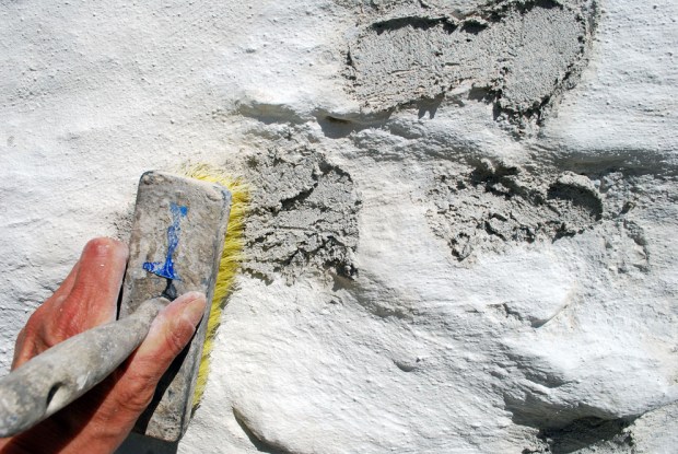 Feit kalkmørtel blandet som hotmix er kastet på de frostskadde områdene og skures hardt inn med kost.