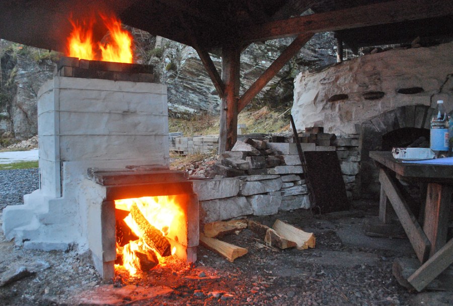 For å holde på varmen, settes det en ring av stein rundt toppen og ladningen dekkes suksessivt til med steinplater. Arbeidet med tildekking er styrt av erfaring for hele tiden å sikre maksimalt god trekk i hele ovnen