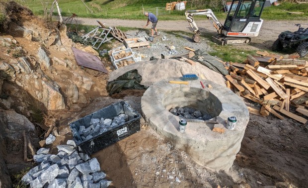 Fylling av kalkovnen fra toppen. Det er en enkel, sirkulær ovn som tar ca. et halvt tonn råmateriale. Det er fylt opp med masse omkring ovnen for å redusere varmetap og få grei tilgang til toppen