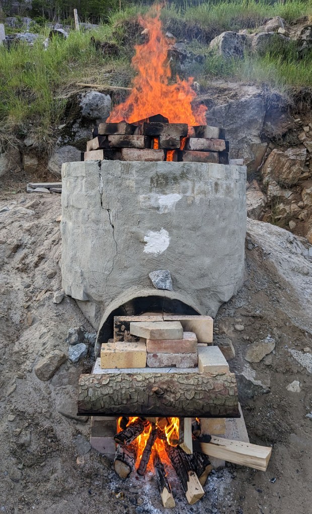 Kalkovnen i full fyr når det nærmer seg avslutning på kvelden. Vi har bygd et temporært forkammer (foran et fast forkammer) for å få opp trekken i ovnen. På toppen er det dekket til med steinplater og teglstein for å minimere varmetap