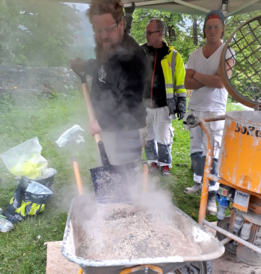 Figur 5: Mørtellesking, eller «hotmix» med brentkalk fra Hyllestad. Det utvikles mye varme ved lesking av kalken i sanden. Vanligvis erstatter man trillebåra og spaden med tvangsblander for å sikre god blanding. Foto: Per Storemyr