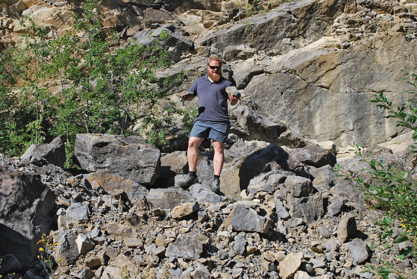 Figur 9: Råstoff til småskala kalkbrenning finner en ofte i nedlagte kalkbrudd. Her på leit etter kalkstein i et gammelt brudd på Toten. Kvalitetsbedømmelse av steinen er ytterst viktig og krever erfaring, ofte også geologiske undersøkelser. Foto: Per Storemyr