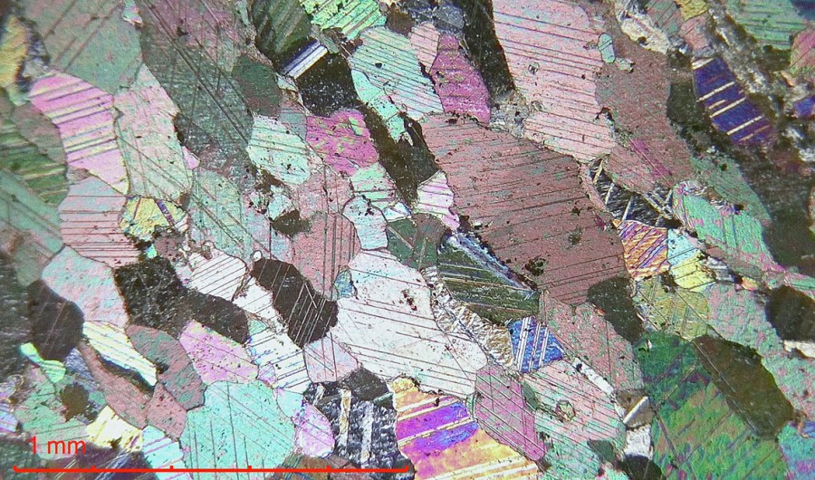 Brevikkalk er en kontaktmetamorf kalkstein - en marmor med kalkspatkrystaller. Den tette, krystalline strukturen gjør den til en "seigbrent" kalk. Mikrobilde, polarisasjonsmikroskop, krysspolarisert lys. Her fra et svært rent parti.