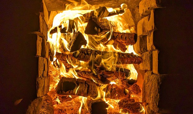 Fyring med kubber på kryss og tvers i hele ovnsåpningen for å trekke varmen lengre foran i oven