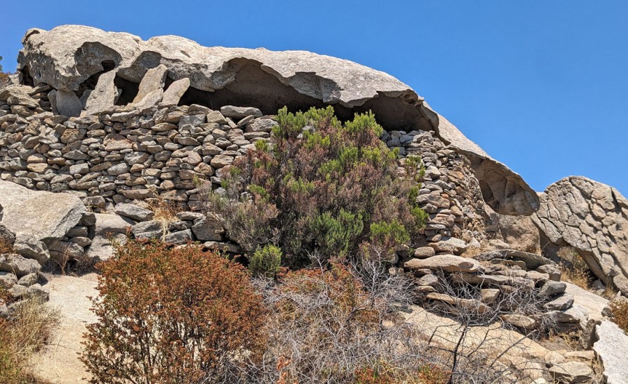 The shelter Capanna de Marco above Cavoli is inside a large tafoni mushroom form, protected around part of the periphery by a stone wall. Photo by Per Storemyr