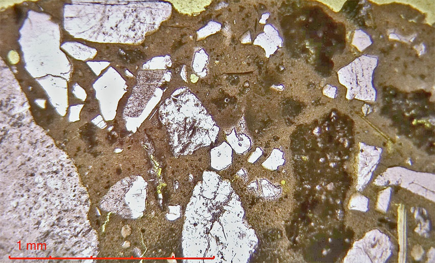 Microphoto of lime mortar based on impure Ringsakr limestone. Fired at tempearture too low to produce slag. The dark elongated fragments are burnt slate/schist components. Photo by Per Storemyr