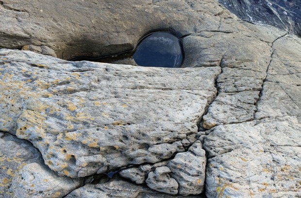 Litt tafoni i skifrig og oppsprukket berg, med en liten jettegryte i nedkant. Foto: PS