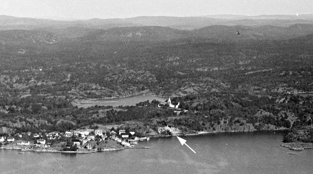 Gruva ses godt som en hvit flekk på flybilde fra første halvdel av 1900-tallet, før større utbygging tok til i Narestø. Flosta kirke er rett overfor gruva. Foto: Daneilsen, fra nb.no