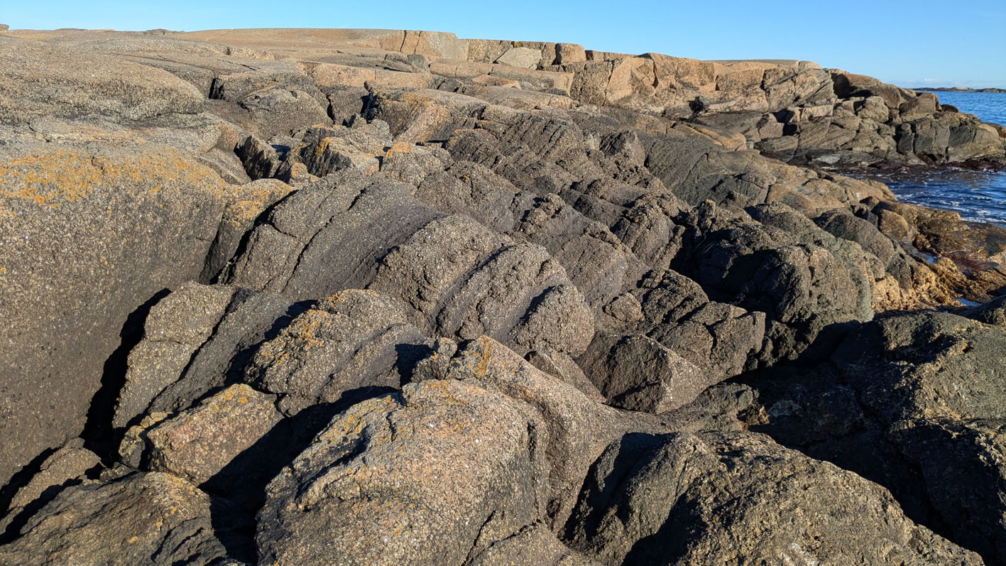 Magmatisk lagning i larvikitt på Rakke, her uten mye tafoni, men med desto mer forvitring langs de mørkere lagene. Foto: PS
